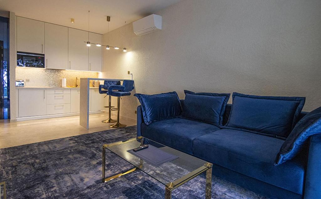 a living room with a blue couch and a kitchen at Apartamenty WRZOS w Perłowej Przystani in Sianozety