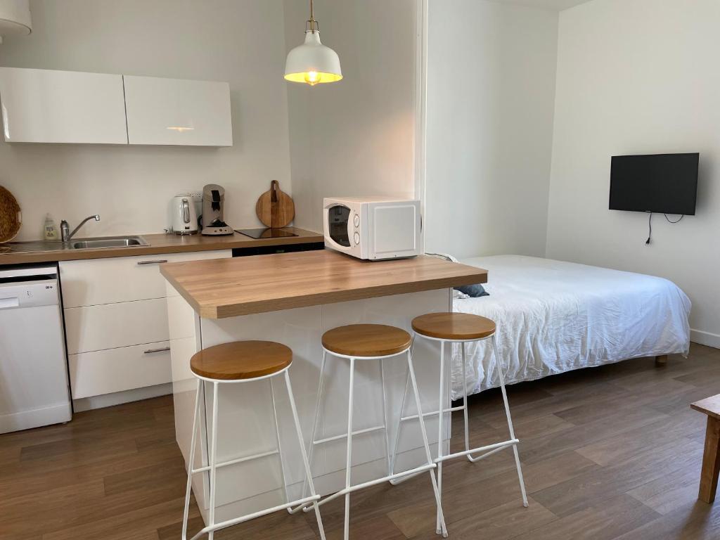 a kitchen with a counter with stools and a bed at Grand Studio centre ville, gare et plage à pied in Pornichet