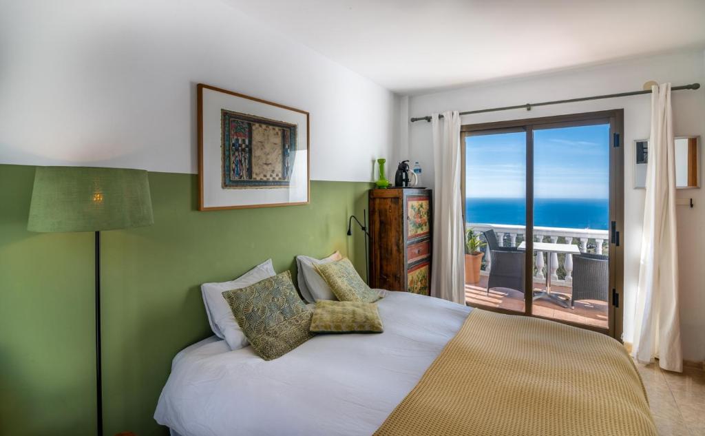 a bedroom with a bed with a view of the ocean at Campo Agave B&B in Sayalonga