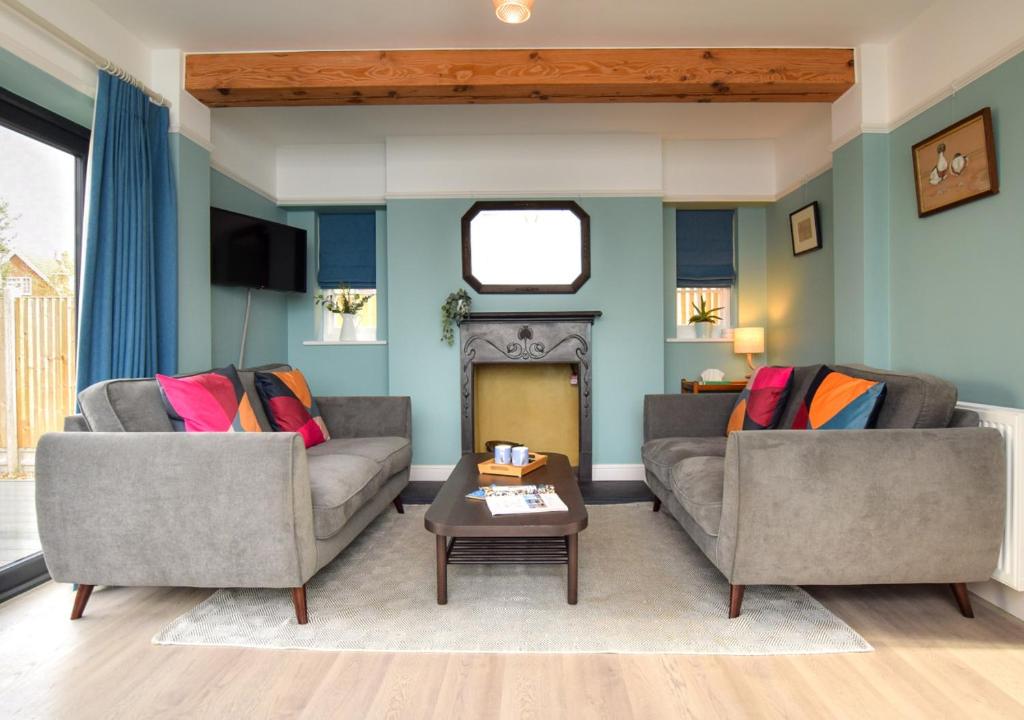 ein Wohnzimmer mit 2 Sofas und einem Kamin in der Unterkunft Rose Cottage - Tankerton in Whitstable
