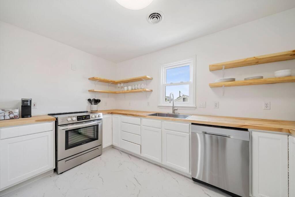 eine Küche mit weißen Schränken und Geräten aus Edelstahl in der Unterkunft Shore Break at CB - 1 Block to Beach Access in Carolina Beach