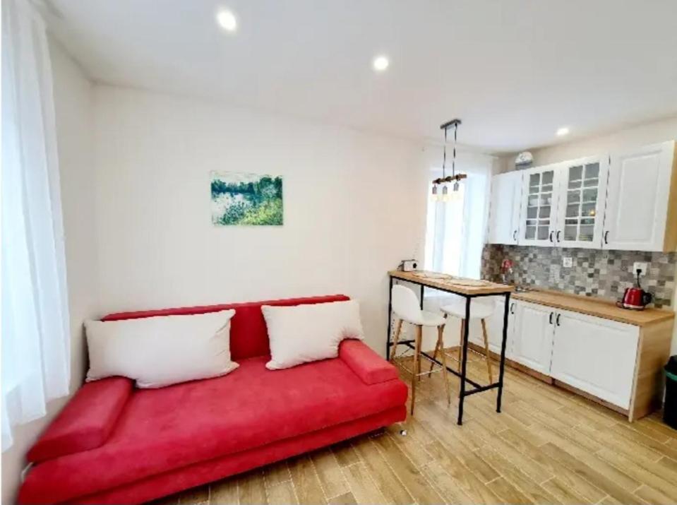 - un canapé rouge dans le salon avec une cuisine dans l'établissement Apartment Iskernik II. - High Tatras, à Vysoké Tatry