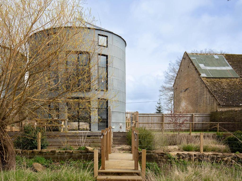 an old silo with a wooden bridge in front of a house at The Silo in Chipping Norton