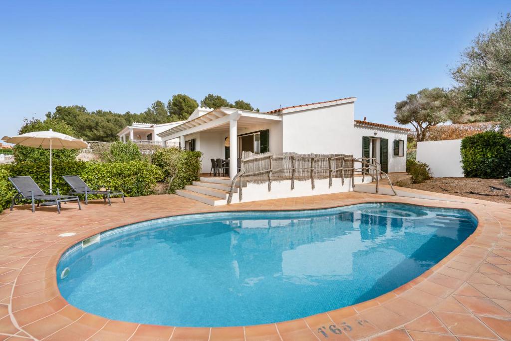 a swimming pool in front of a house at Villas Menorca Sur in Son Bou