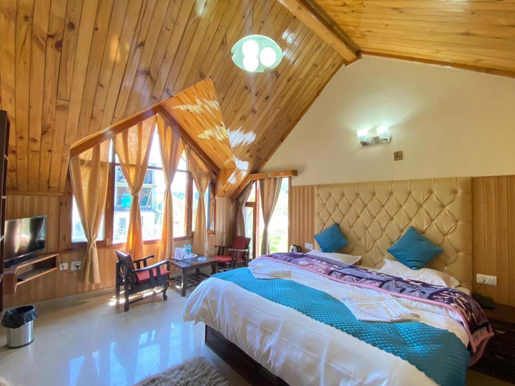 a bedroom with a large bed in a room with wooden ceilings at Himalayan Ecstacy in Manāli