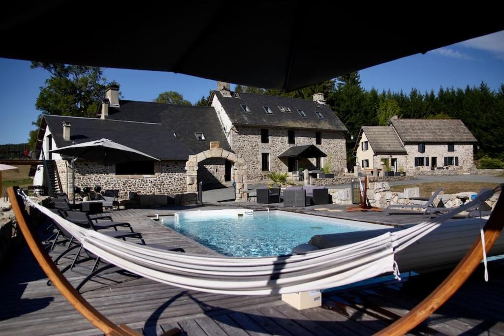 a hammock in front of a house with a pool at Domaine des Annouillards in Sornac
