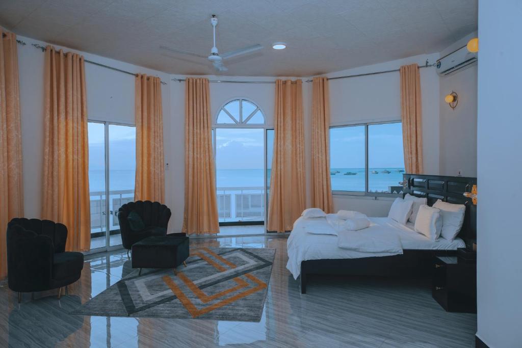 1 dormitorio con 1 cama, 2 sillas y ventanas en ST Beach Villa, en Kibweni