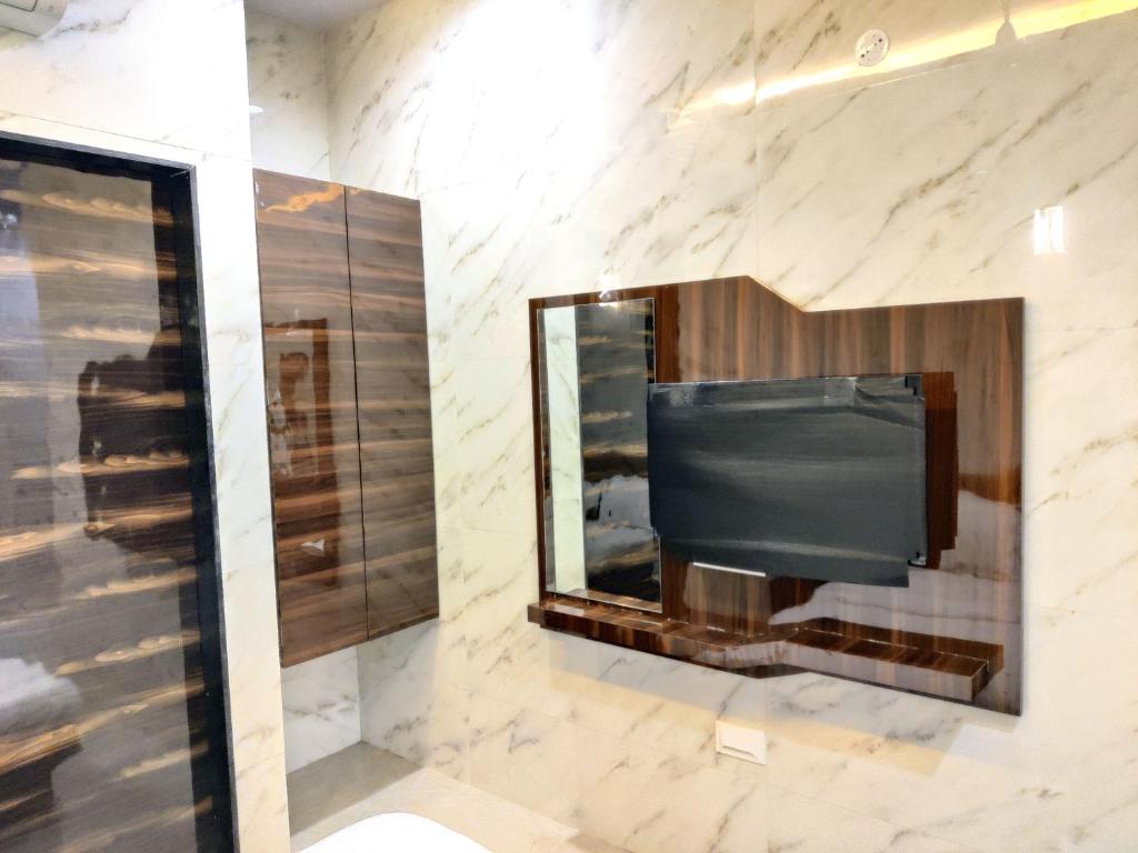 孟買的住宿－Hotel Comfy Inn，石墙内的电视,带镜子