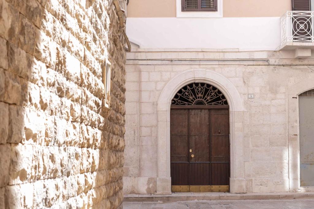 a building with a brown door and a brick wall at B&B Longobardi in Trani