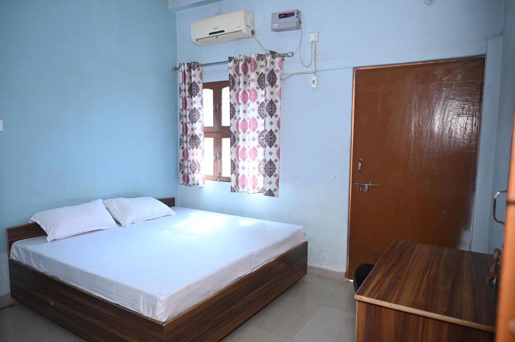a bedroom with a bed and a window and a table at Mahamaya Paying Guest House in Varanasi