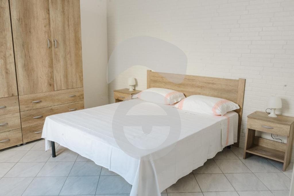 1 dormitorio con cama blanca y cabecero de madera en la casa celeste di Paf, en Torre Suda