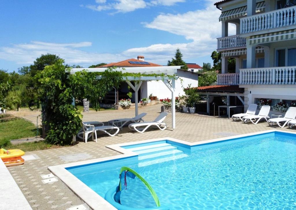 a swimming pool in front of a house at Apartments Gorančica in Malinska