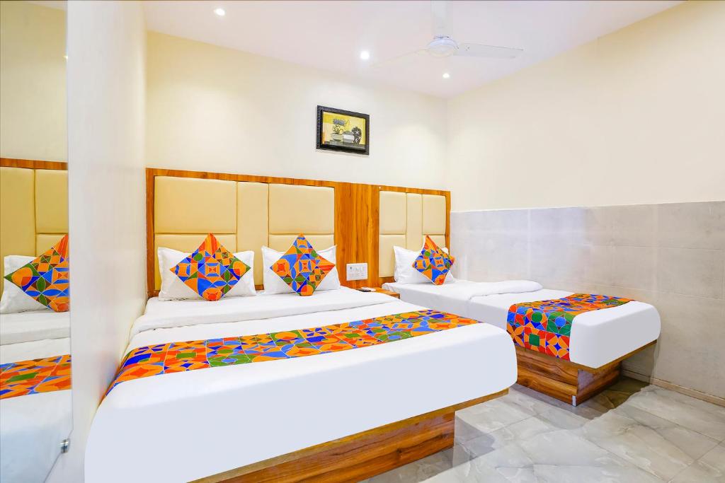um quarto com 2 camas e almofadas coloridas em FabExpress Emirates Suits em Mumbai