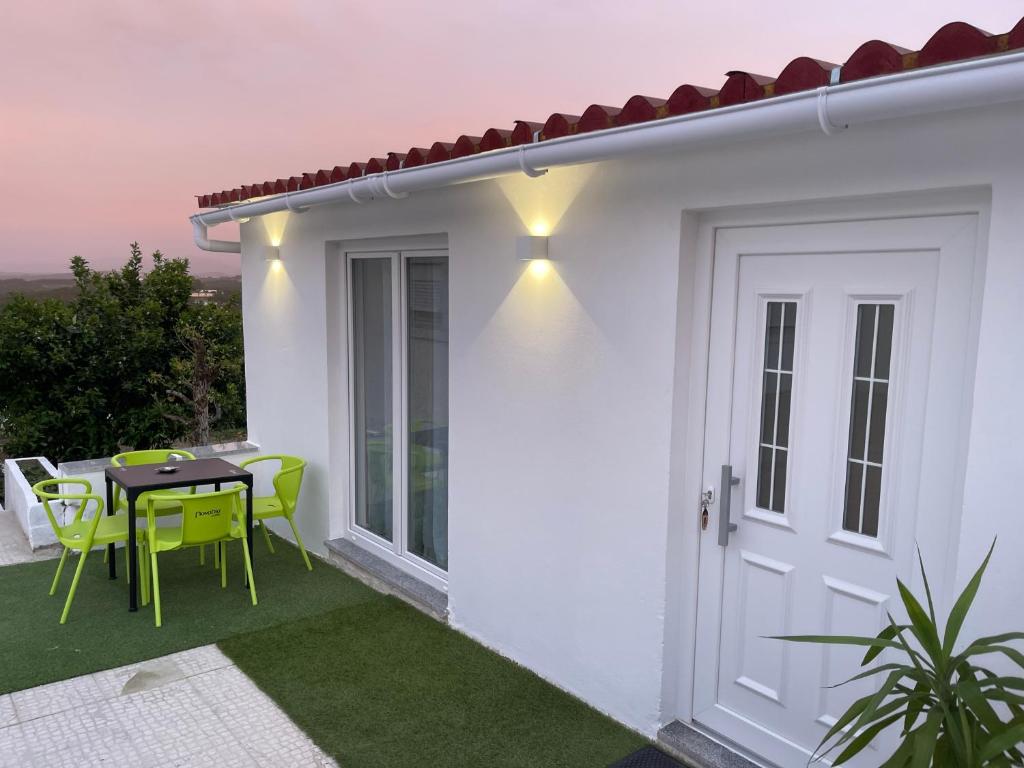 a white house with a patio with a table and chairs at Neto Pinto - Casa de férias / fins de semana. in Lourinhã