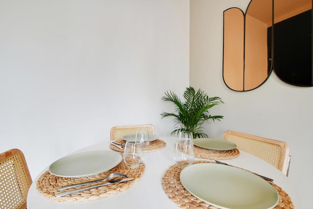 a white table with plates and glasses on it at Luxury Cocon by Les Maisons de Charloc Homes in Boulogne-Billancourt