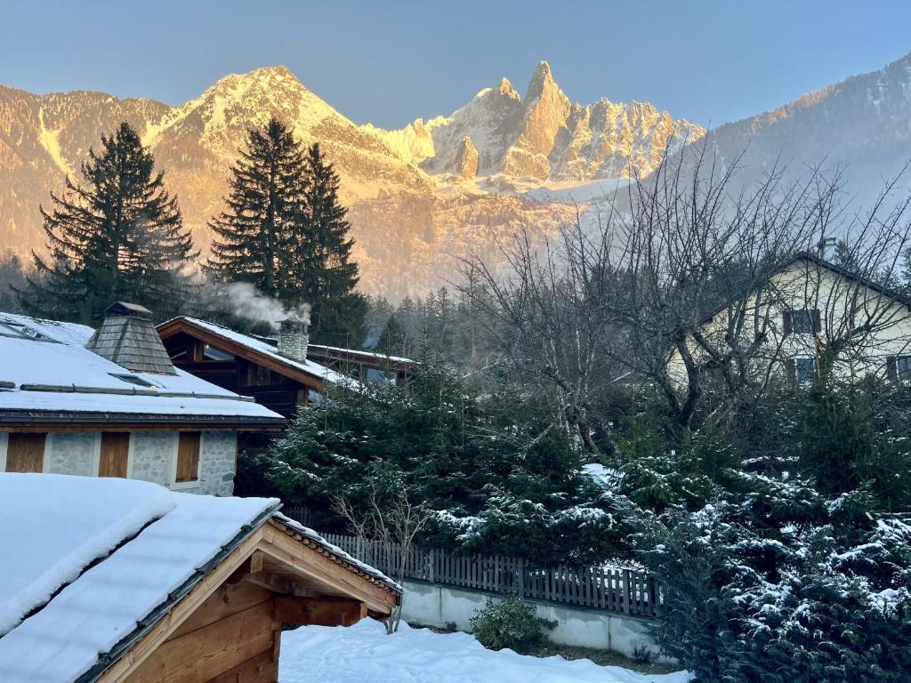 una casa cubierta de nieve con montañas en el fondo en Le Chaney - T2 dans chalet - Massif du Mont-Blanc, en Chamonix-Mont-Blanc