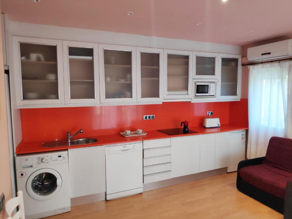 ラ・ピネーダにあるApartamentos Estival 3000の白いキャビネットと赤い壁のキッチン