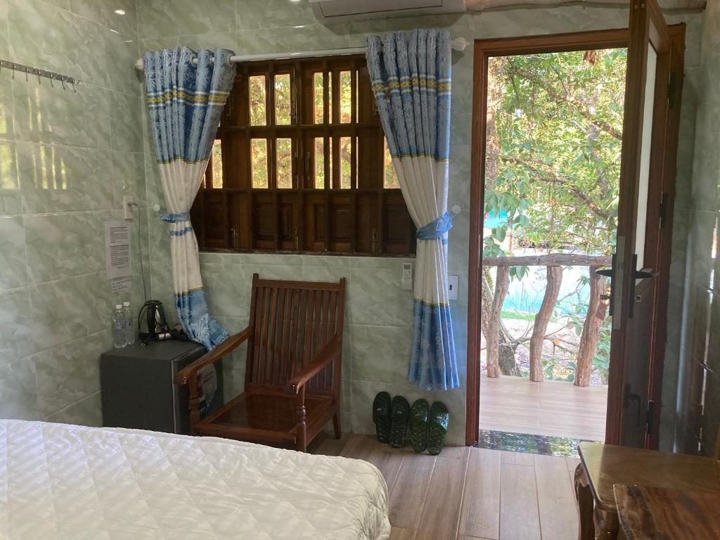 a bedroom with a bed and a chair and a window at Cát Tiên Hotel in Cat Tien