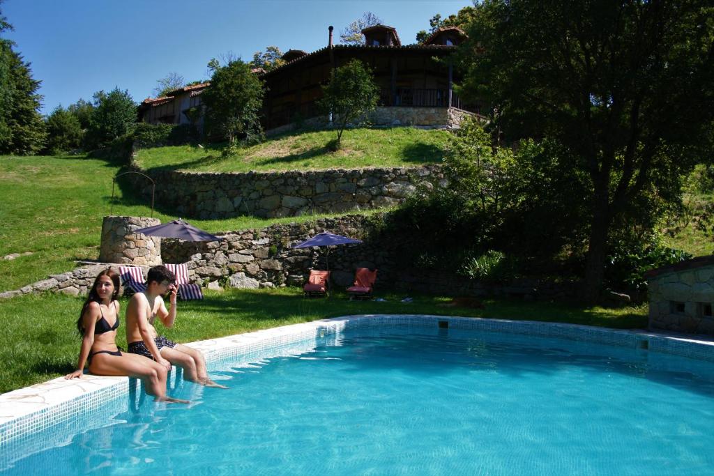 dos mujeres sentadas en el borde de una piscina en Hotel Rural Abejaruco, en Cuevas del Valle