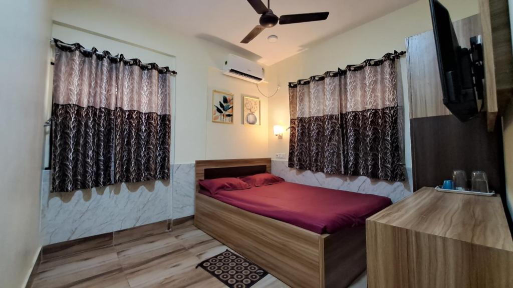 1 dormitorio con 1 cama, TV y cortinas en Laxmi Niwas, Salt Lake, Kolkata, 10mins from Sector 5, en Calcuta