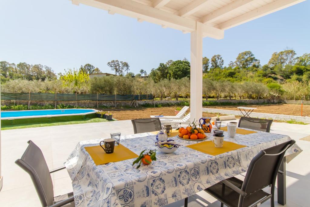 - une table et des chaises sur une terrasse avec piscine dans l'établissement White Villa With Swimming Pool - Happy Rentals, à Ispica