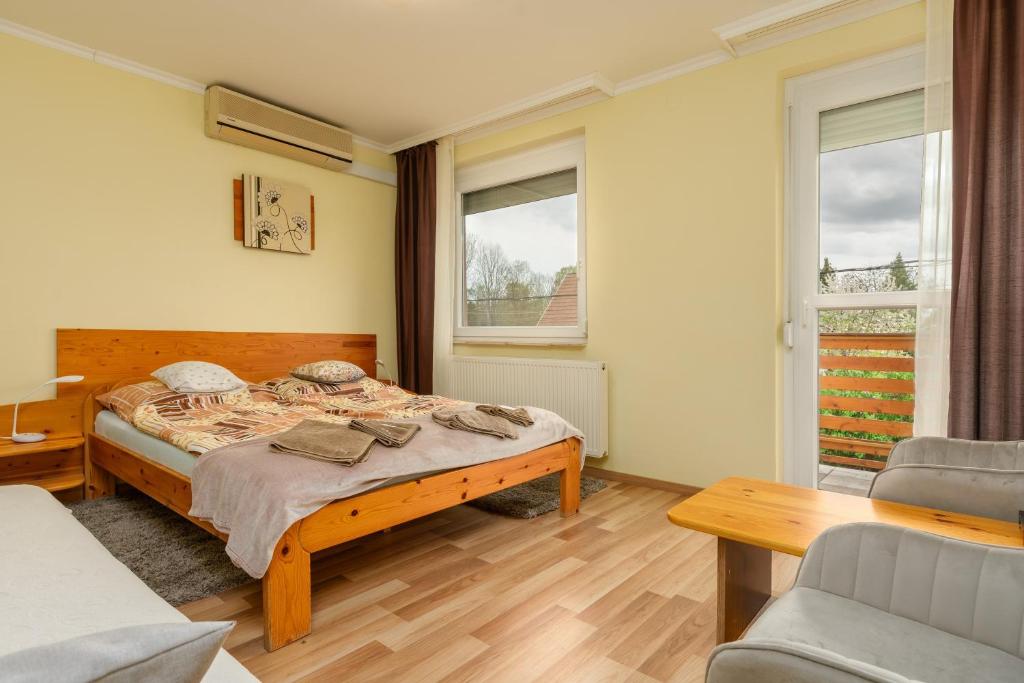 a bedroom with a bed and two windows at Janika Pension in Vonyarcvashegy
