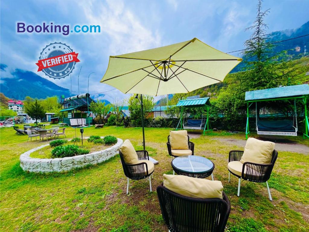Himalayan Nature Walk Resort, Manali في مانالي: مجموعة كراسي وطاولة مع مظلة