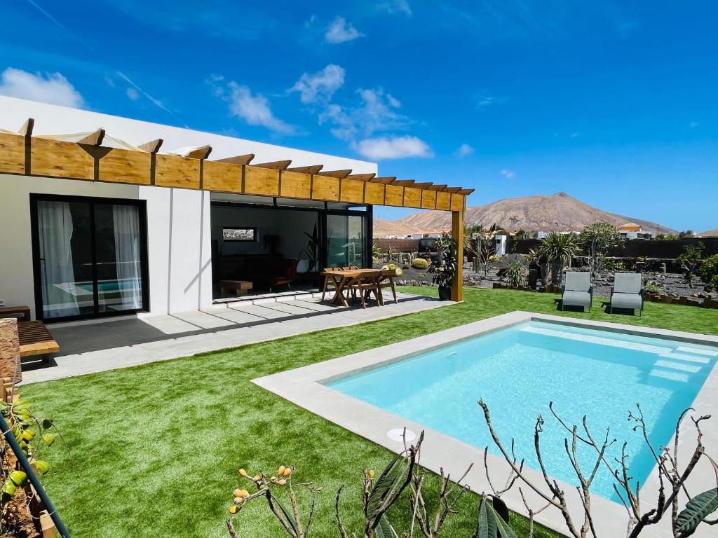 a backyard with a swimming pool and a house at Bungalow + Piscina independiente in La Oliva