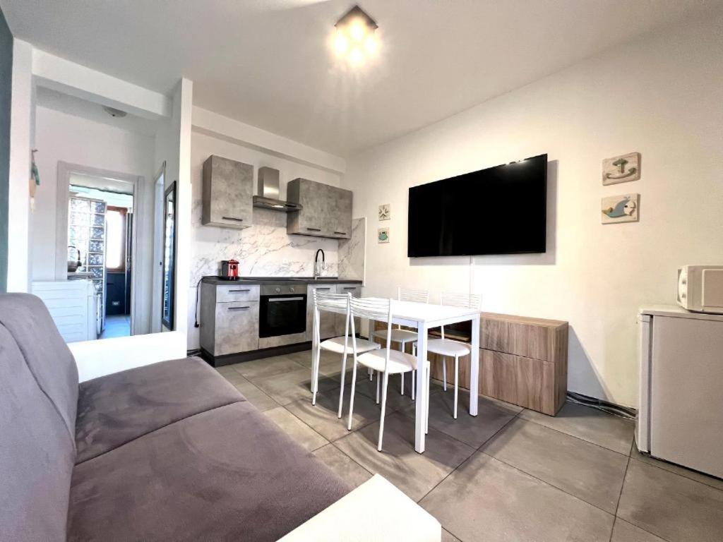 ein Wohnzimmer mit einem Sofa und eine Küche mit einem Tisch in der Unterkunft Be Your Home - Casa Vetulonia in Santa Marinella