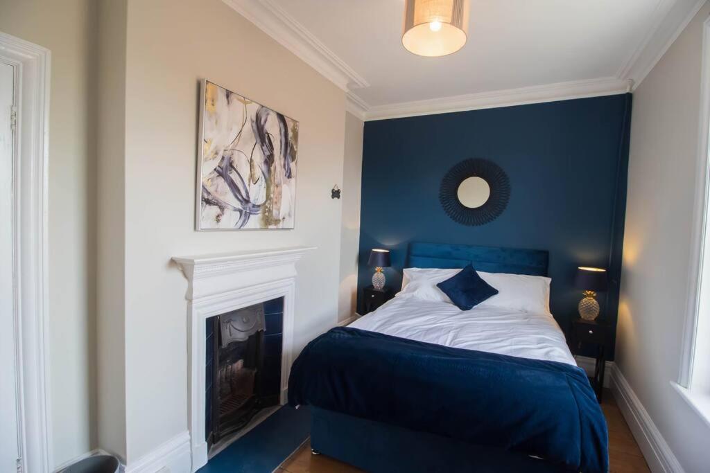 a blue bedroom with a bed and a fireplace at Beach Haven Apartment By Air Premier in Seaford