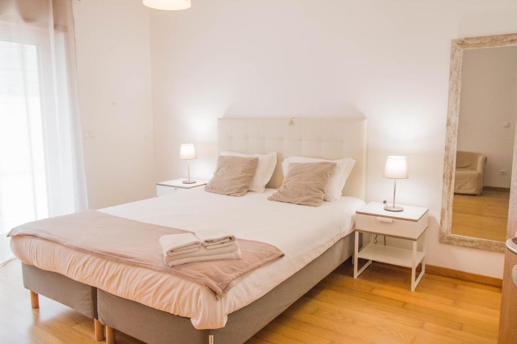 a bedroom with a large white bed with two lamps at Casas e Quintas de Praia in Praia da Barra