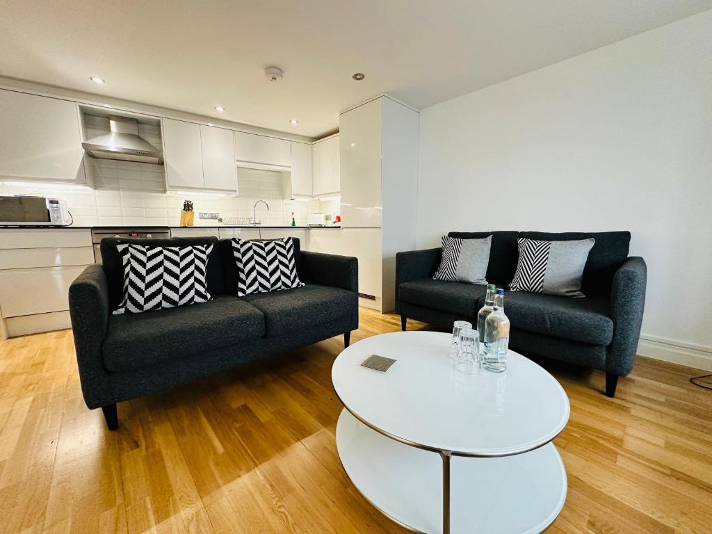 a living room with two black couches and a white table at West Street Mews - Serviced Accommodation in Exeter