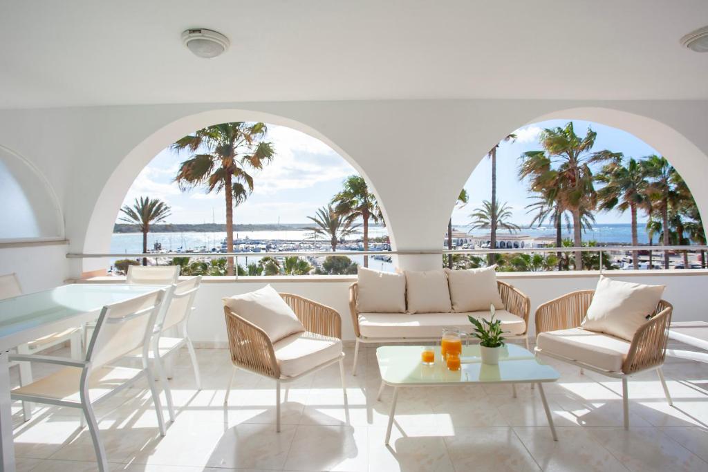 - un hall avec des chaises, des tables et des palmiers dans l'établissement Apartaments Edificio Puerto, à Colonia Sant Jordi