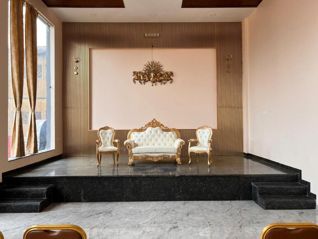 een woonkamer met een bank en 2 stoelen bij Krishna Vatika Hotel in Shivāpur