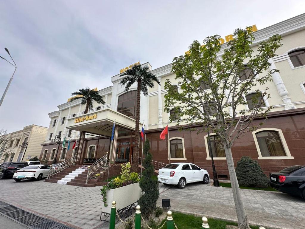 un coche blanco estacionado frente a un edificio en Zilol Baxt Hotel, en Samarkand