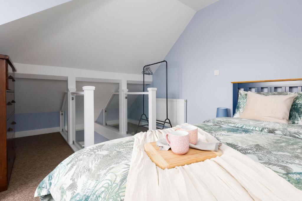 a bedroom with a bed with two pink cups on a tray at Chic 2-Bed Seafront Haven Near Felpham Beach in Felpham