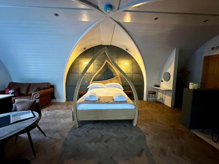 a bedroom with a bed with an arched ceiling at Badger at Owlet Hideaway - with Hot Tub, near York in Seaton Ross