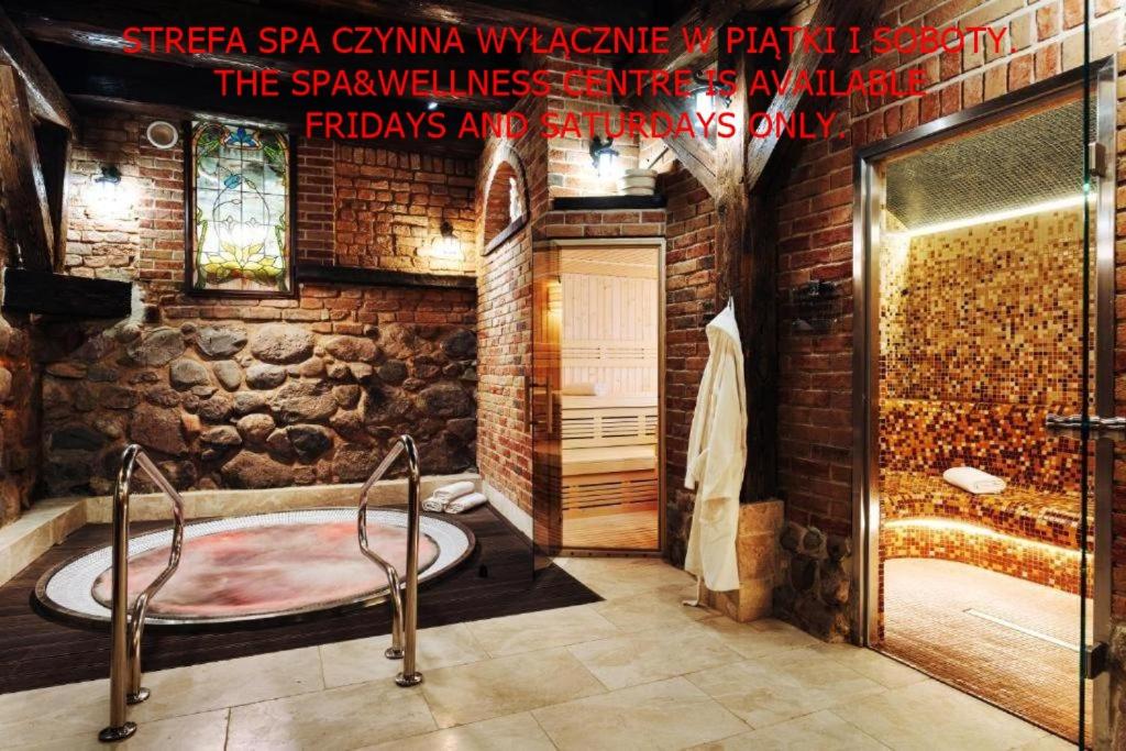 a bathroom with a tub and a stone wall at Hotel Legenda in Toruń