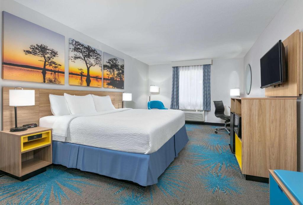 a hotel room with a bed and a flat screen tv at Days Inn & Suites by Wyndham Cabot in Cabot