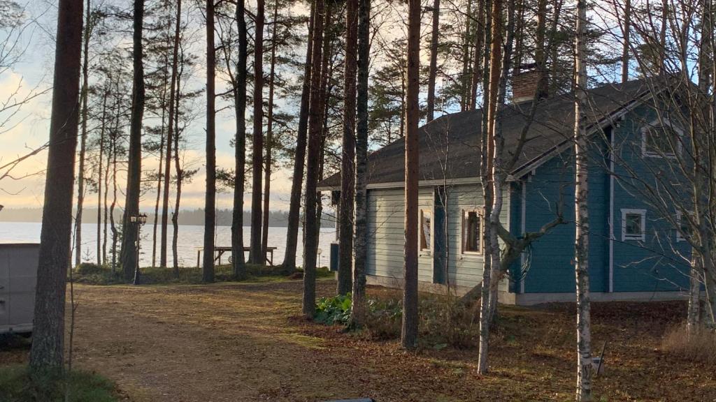 une maison bleue dans les bois à côté d'une route dans l'établissement Huvila Pahkaranta Lestijärven rannalla, à Lestijärvi