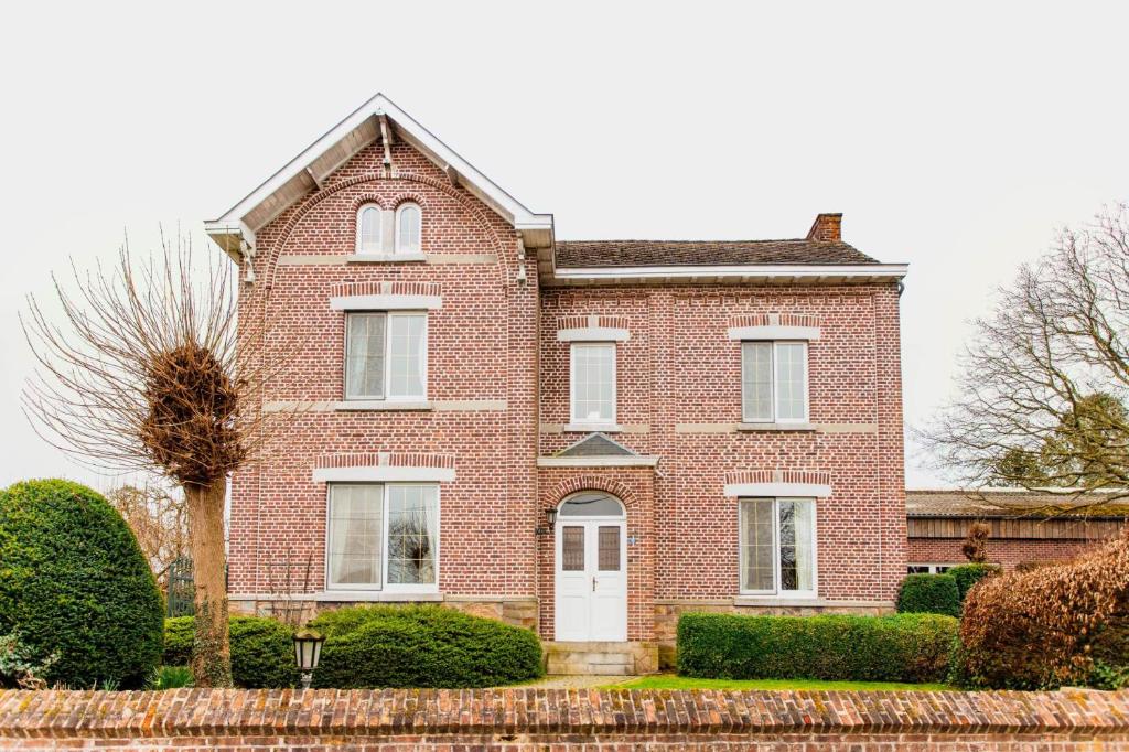 een rood bakstenen huis met een witte deur bij Beautiful mansion with swimming pool in Bilzen