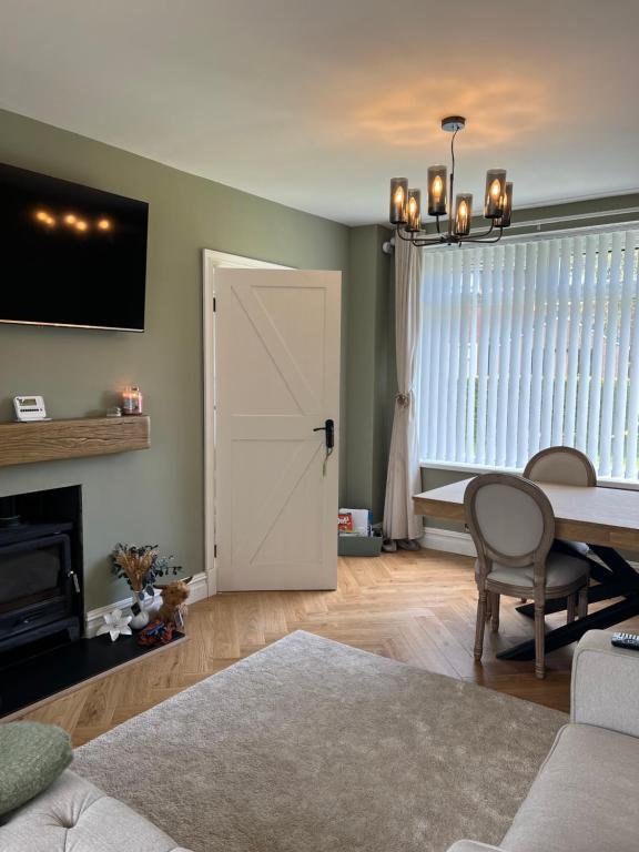 a living room with a dining room table and a door at The hidden cottage in Wythenshawe