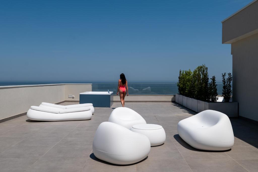 a woman walking on top of a building with white chairs at Hotel Sporting Riccione in Riccione