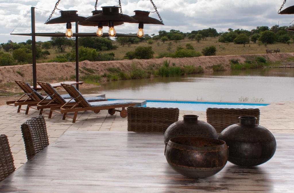 a table with two large vases and chairs next to a river at Casa de la Presa 3 in Polokwane