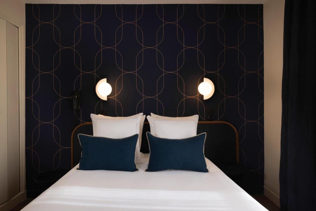 a bedroom with a bed with two blue pillows at Bijou Hôtel Paris Boulogne in Boulogne-Billancourt