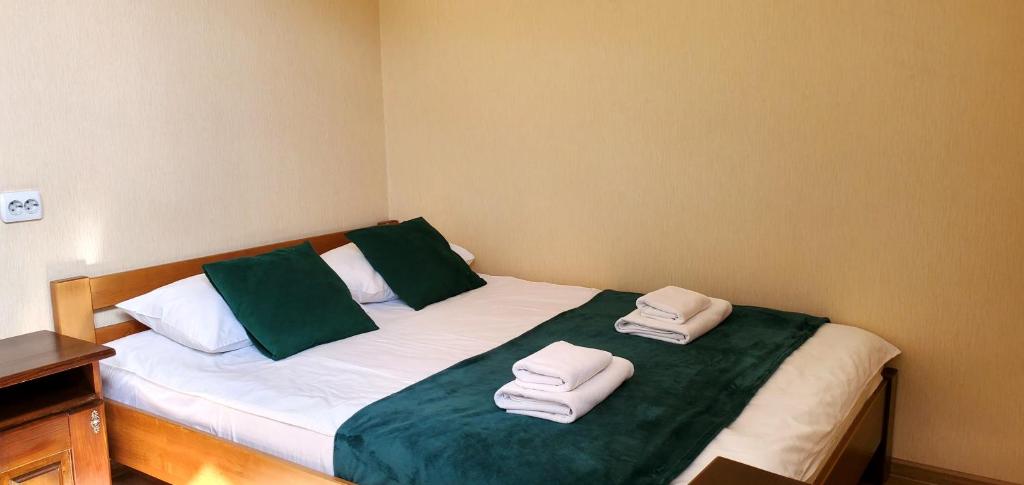 Una cama con dos toallas verdes y blancas. en Etna Hotel, en Leópolis