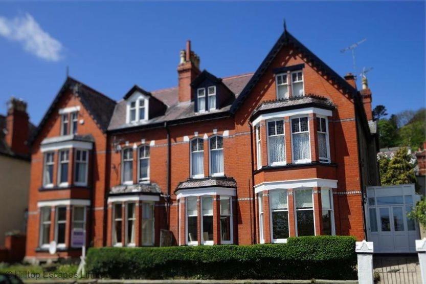 a large red brick house with white windows at No22, Llandudno - Stylish & Cosy Period Apartment, with Hot Tub & Private Parking in Llandudno