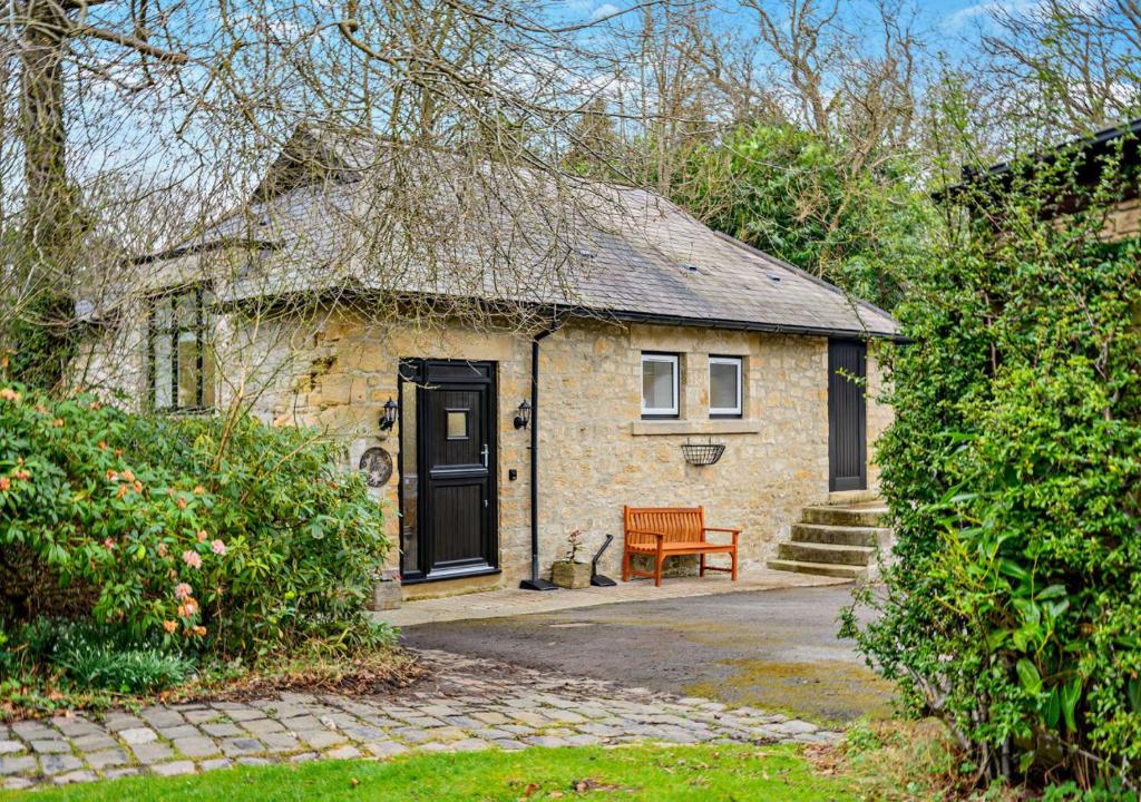 a small brick house with a black door and a bench at Honey Hirst in Shotley Bridge
