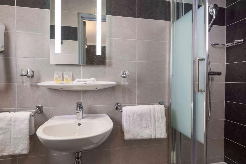 a bathroom with a sink and a mirror at Bijou Hôtel Paris Boulogne in Boulogne-Billancourt