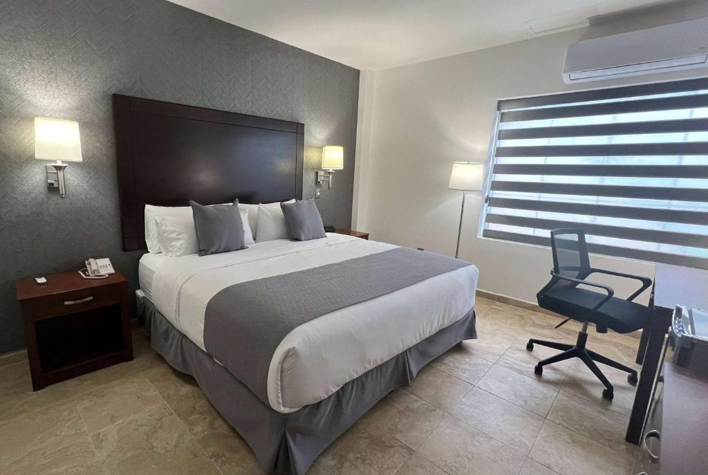 a hotel room with a large bed and a chair at La Quinta by Wyndham Reynosa in Reynosa